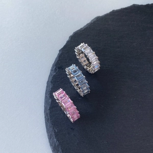 Macro shot of S925 silver eternity rings featuring emerald-cut white, blue, and pink zircons