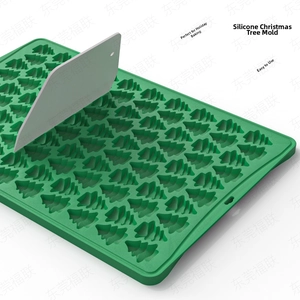Detailed view of green Christmas tree silicone chocolate mold with a gray scraper tool
