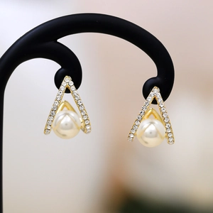 Macro shot of long gold geometric pearl earrings with shimmering crystal accents