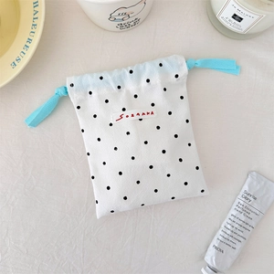 Close-up of a mini drawstring bag with black polka dots and blue braided cords