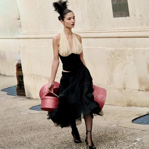 Elegante top halter bicolore e gonna nera abbinati a calze a rete per un look di classe