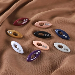 Detail of colorful oval scarf clips with rhinestones on brown satin fabric