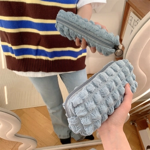 Close-up of light blue bubble textured fabric pouch with a round metal zipper pull