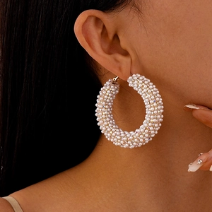 Detailed close-up of large round hoop earrings with white pearls and gold metal accents