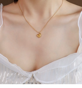 Close-up of a 18k gold plated stainless steel heart pendant necklace on a model's neck