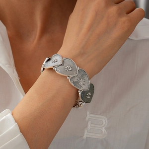 Close-up of vintage heart link bracelet with sunflower patterns on model wrist