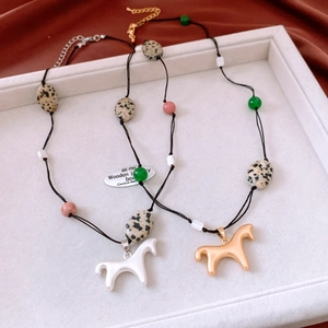 Détail du collier de perles en pierre avec pendentif cheval et perles de marbre tachetées