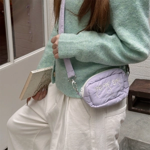 Detail of light purple crossbody bag with bow embroidery and adjustable shoulder strap