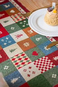 Macro detail of Christmas plaid table runner with gold thread weaving and elk patterns