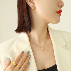 Parure de bijoux dorée minimaliste avec boucles d'oreilles et collier portés par un modèle
