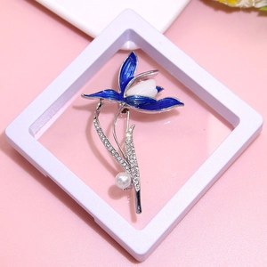 Detail view of blue enamel flower brooch with pearls and rhinestones on a display stand