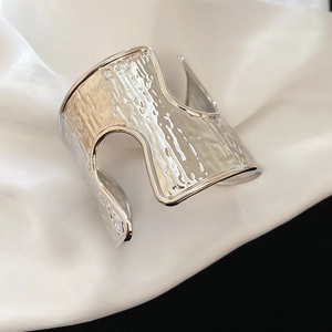Detailed view of silver irregular wide open bangle with textured hammer finish on satin