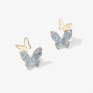 Macro detail of layered butterfly earrings with blue crystals and gold plating