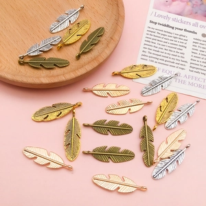 Close-up of vintage alloy leaf wing pendants in gold, silver and bronze for DIY jewelry