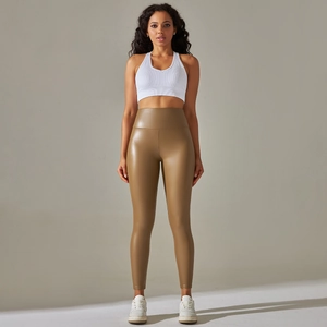Detail of high waisted tan faux leather leggings with tight fit and glossy finish