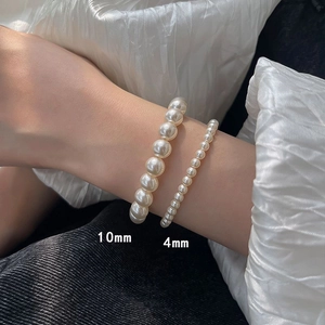Detail of 10mm and 4mm pearl elastic bracelets worn on wrist with elegant luster