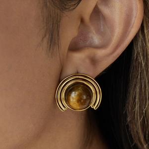 Close-up of 18K gold stainless steel ribbed earrings with brown natural stone on model