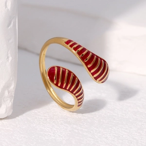 Detail of red enamel water drop ring with golden vertical lines on stone surface