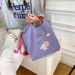 Detail of cute elephant embroidery on a purple nylon tote bag with drawstring straps