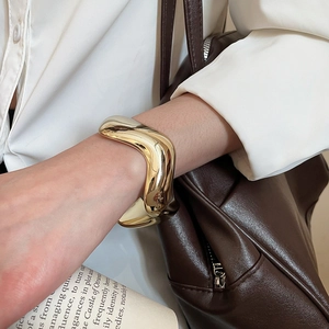 Détail d'un bracelet jonc ondulé doré minimaliste avec une finition miroir hautement polie