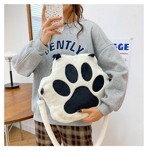Close-up of soft black and white plush cat paw crossbody bag with furry shoulder strap
