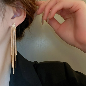 Detailed view of long gold chain tassels earring with elegant v-shape design on woman's ear