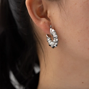 Close-up of a silver bamboo style hoop earring worn by a model to show size and scale