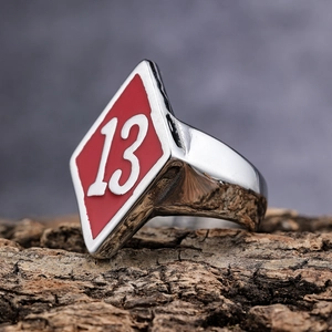 Macro side view of stainless steel ring with red enamel number 13 on a wooden stand