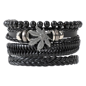 Close-up of multilayer black leather bracelets featuring a metal marijuana leaf charm