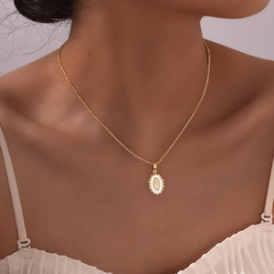 Close-up of golden necklace with oval Virgin Mary pendant on model's neck