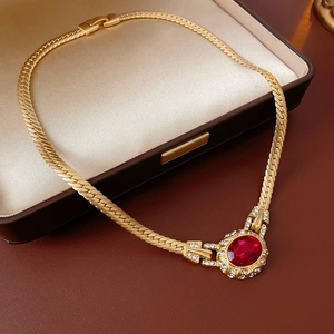 Close-up of a vintage gold snake chain necklace with a red oval gem and diamond halo