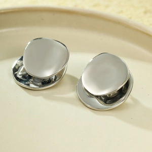 Detailed view of silver stainless steel geometric earrings on a beige ceramic plate