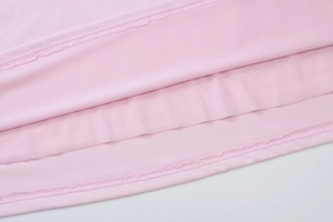 Dettaglio della cucitura a doppio ago e bordo tagliacuci sul vestito a pieghe rosa