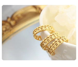 Detailaufnahme von drei Goldkettenringen mit Perlenkanten auf einer weißen Keramiktasse