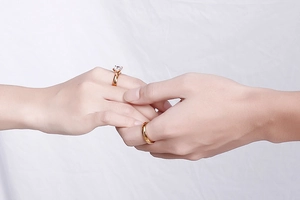 Detail of gold-plated wedding ring set with six-prong solitaire and smooth band on finger