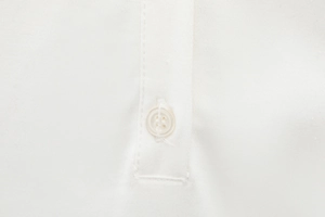 Macro detail of the white four-hole button and precision stitching on the shirt collar