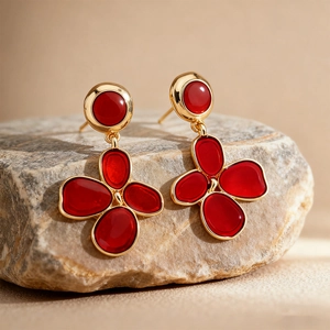 Close-up of red and gold floral earrings with enamel finish on natural stone
