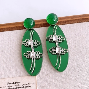 Détail de boucles d'oreilles ovales en résine verte vintage avec nœuds argentés