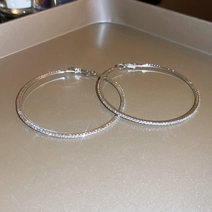 Detailed view of silver hoop earrings with shimmering rhinestones on a gold tray