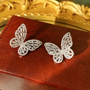 Macro shot of silver butterfly stud earrings with clear zircon stones on brown leather box