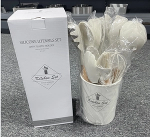 Dettaglio degli utensili da cucina in silicone crema con manici in legno e secchiello bianco