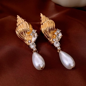 Close-up of vintage golden shell earrings with sparkling crystals and pearl pendants