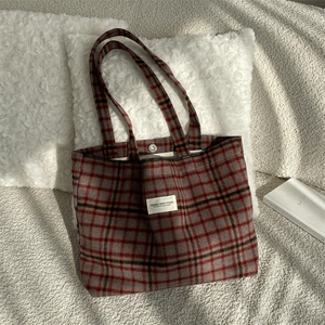 Close-up of retro plaid tote bag showing silver snap button and canvas texture