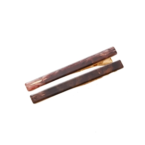 Macro detail of two brown marble resin hair clips with golden metal clasp mechanisms