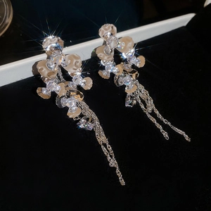 Detailed macro view of sparkling zircon flower earrings with long metal chain tassels