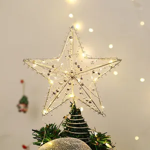 Silver metal wire star Christmas tree topper with warm LED lights on a green tree