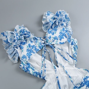 Detail of floral backless dress featuring blue floral print and ruffled back tie straps