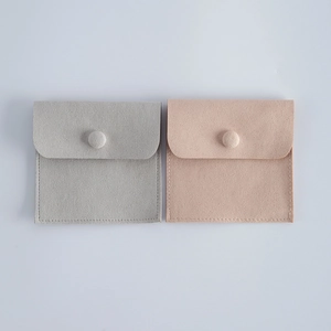 Macro detail of soft velvet jewelry pouches in pink and grey with snap button closure