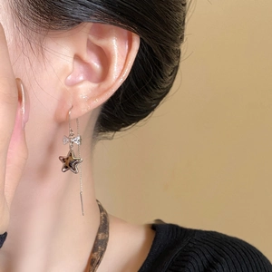 Close-up of leopard star pendant earrings with bow detail and long silver tassel chains