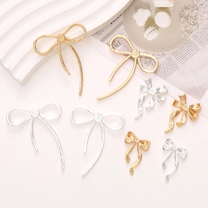 Elegant gold and silver bow-shaped metal alloy charms in multiple sizes on a display